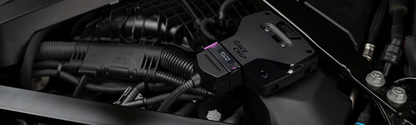 RaceChip GTS 5 Black control unit installed in an engine bay with the OEM connector plugged in.